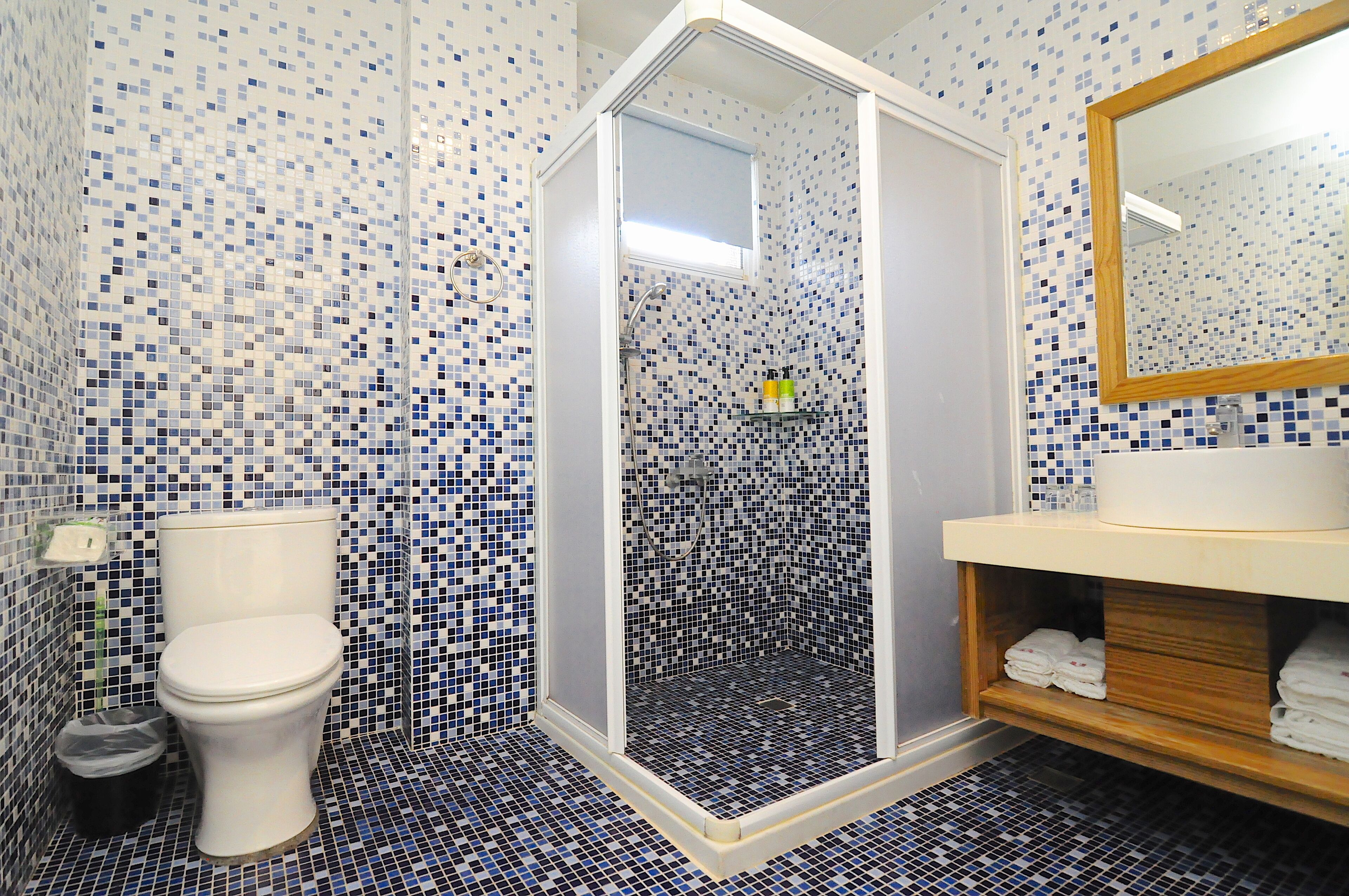 Een badkamer met toilet, douche met glazen deur en wastafel met spiegel.