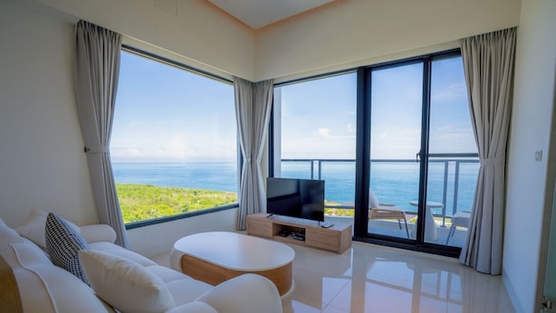 A modern living room with a large TV, white furniture, and a balcony with a view of the sea. - Star Sea B&B (Liuqiu)