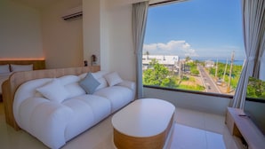 A modern hotel room with a large window, a white sofa, and a wooden coffee table. - Star Sea B&B (Liuqiu)