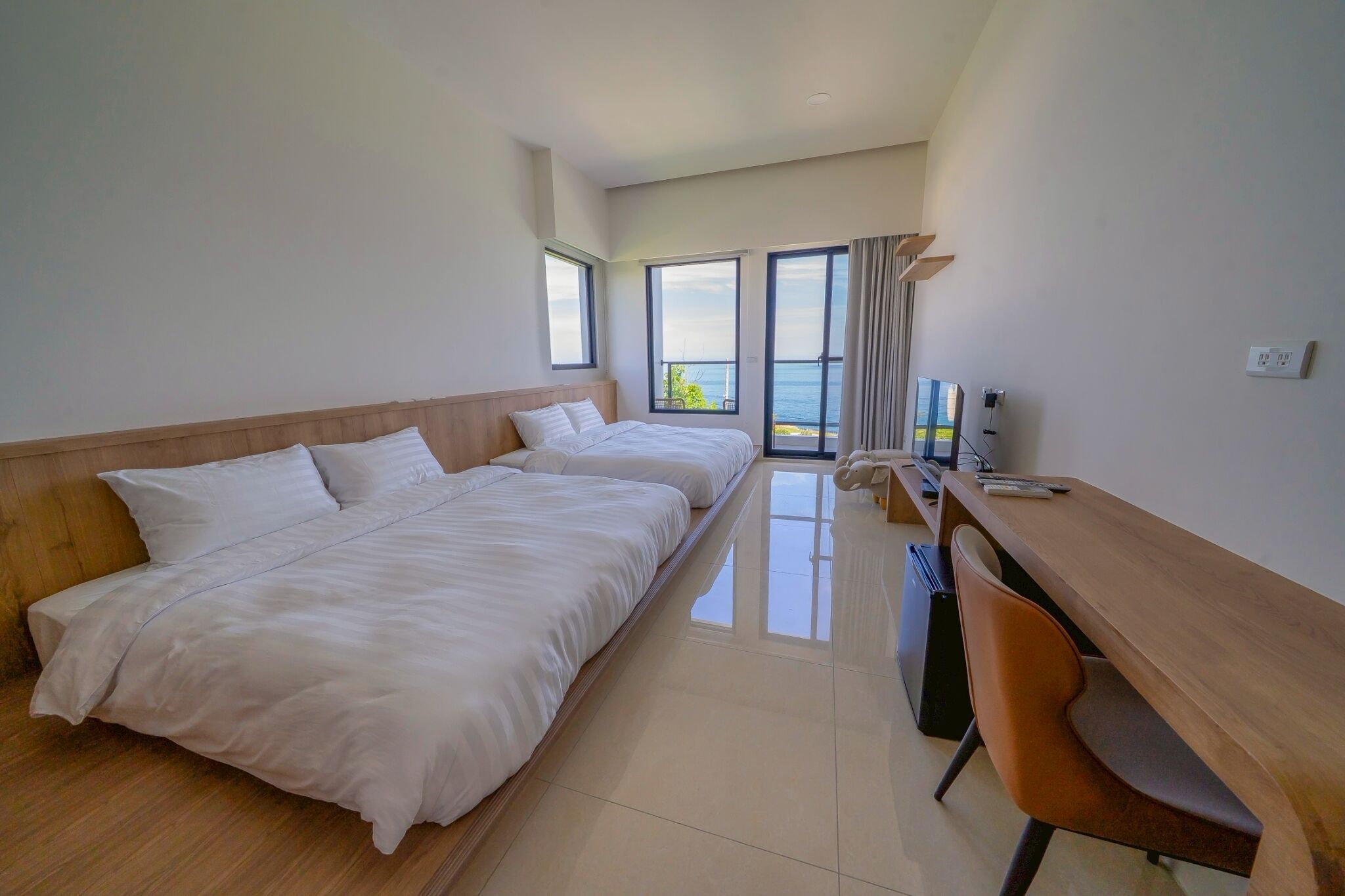 A hotel room with two beds, a desk, and a chair.