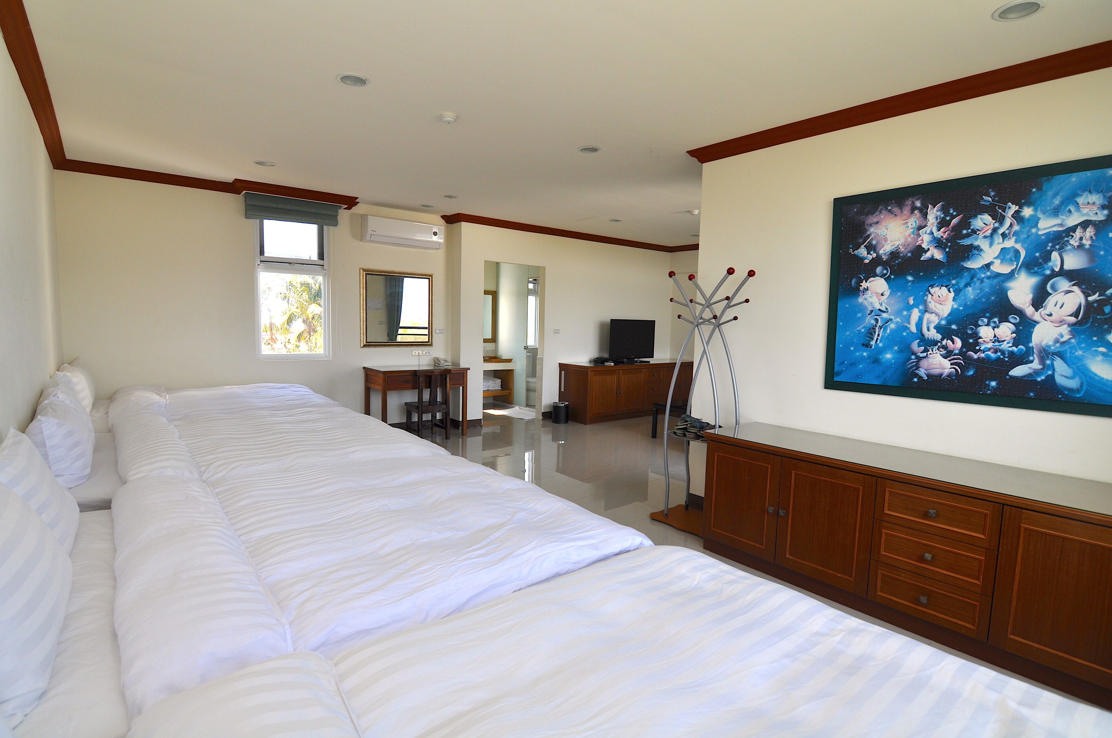 Une chambre d’hôtel avec un grand lit, une armoire en bois, une télévision et un tableau au mur.