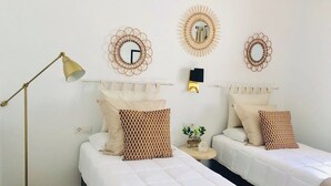 Une chambre d’hôtel avec deux lits, une table de chevet avec une lampe et des miroirs décoratifs sur les murs.