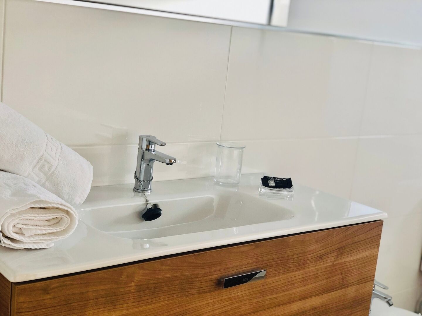 Ein Badezimmer mit einem weißen Waschbecken, einem Handtuch und einer Seifenspender.