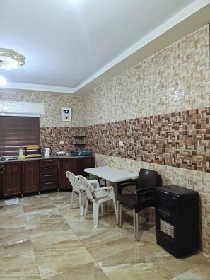 A compact kitchen with a dining area, featuring a patterned backsplash, a built-in stove, and a dining table with chairs.