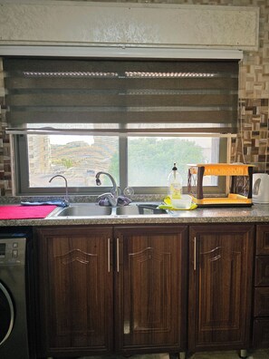 A kitchen with a built-in sink, a microwave, and a window with a view of the outside. - Private Family Apartment - Very Quiet Location (Amman)