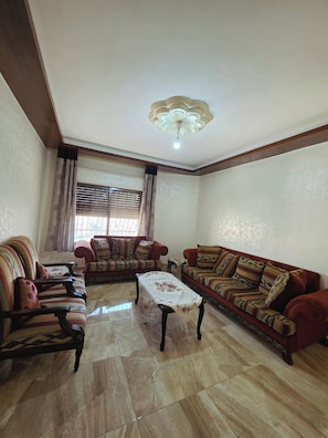A living room with two sofas, a coffee table, and a ceiling light fixture. - Private Family Apartment - Very Quiet Location (Amman)