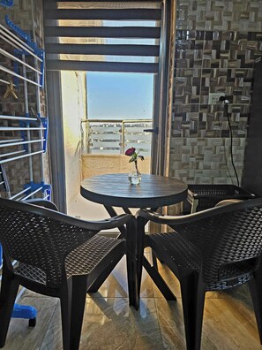 A balcony with a view of the city, a table with chairs, a vase with a flower, and a blue drying rack. - Private Family Apartment - Very Quiet Location (Amman)