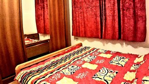 A bedroom with a bed, a wooden wardrobe, and a mirror. - Private Family Apartment - Very Quiet Location (Amman)