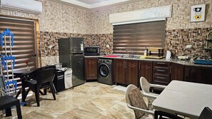 A compact kitchen with a washing machine, a refrigerator, and a microwave.