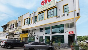 Un hotel con un llamativo letrero que dice 'OYO First Garden Hotel', múltiples unidades de aire acondicionado y una entrada visible.