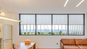 Una cocina moderna con una mesa y sillas de madera, un sofá de cuero y un ventanal con vistas al mar.