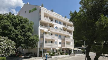 Ein mehrstöckiges Hotel mit Balkonen, einem Fahrradverleihschild und einem geparkten Auto davor.
