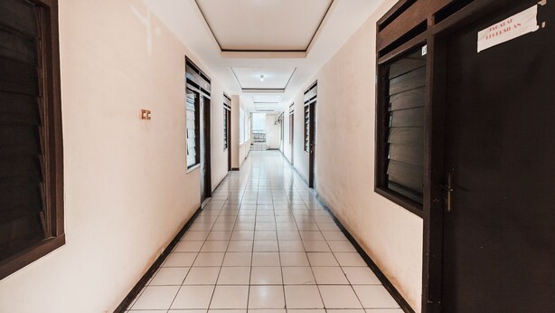 A long, narrow hallway with tiled floors and doors on both sides.