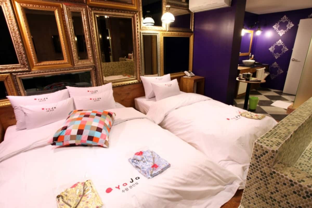 A hotel room with two beds, a vanity with a mirror, and a checkered pillow.