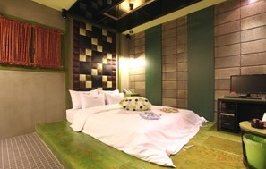 A neatly made bed with pillows and a blanket, a television on a stand, and a green trash bin. - Hotel Yaja Suwon City Hall (Suwon)