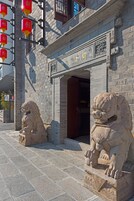 Un edificio tradicional con estatuas de leones de piedra en la entrada, fachada de ladrillo y un letrero con caracteres chinos.
