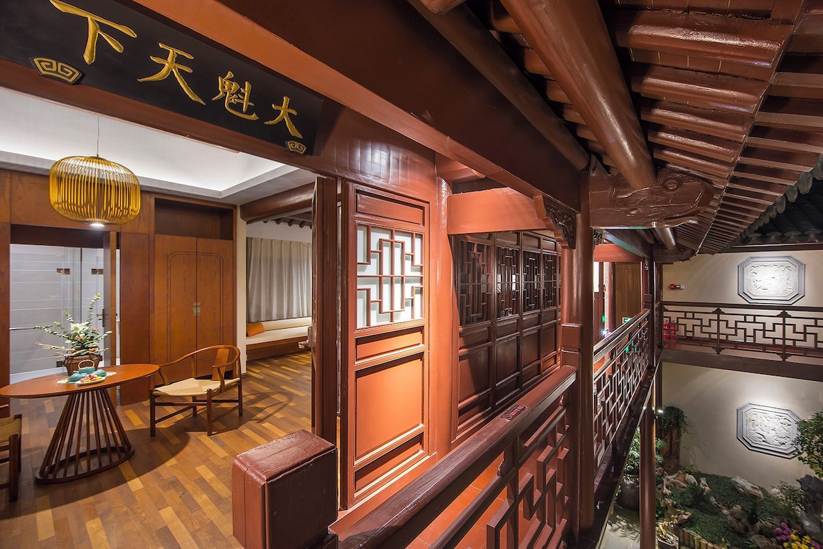 A traditional Chinese-style interior with wooden architecture, a balcony with a view of a courtyard, and a dining area with a table and chairs.