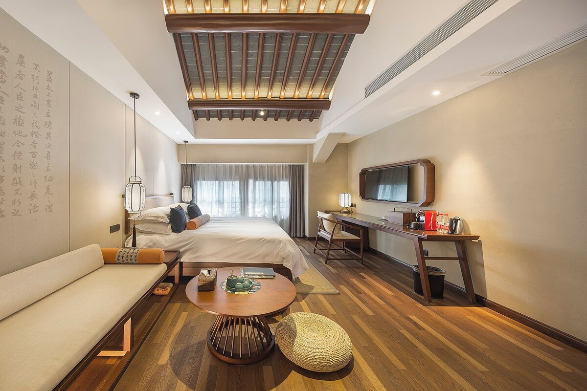 A hotel room with a bed, sofa, desk, and a television.