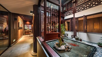 Un interior tradicional con arquitectura de madera, un pequeño jardín interior y suelo de baldosas.