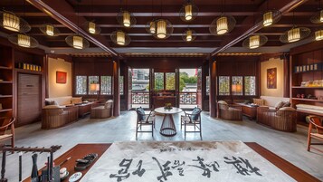 Un interior de estilo tradicional con muebles de madera, una mesa redonda central y faroles colgantes.