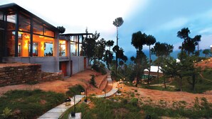 A modern house with large windows, a stone foundation, and a stone pathway leading to the entrance. - Queens Meadows by Sunshine & Smiles (Ranikhet)