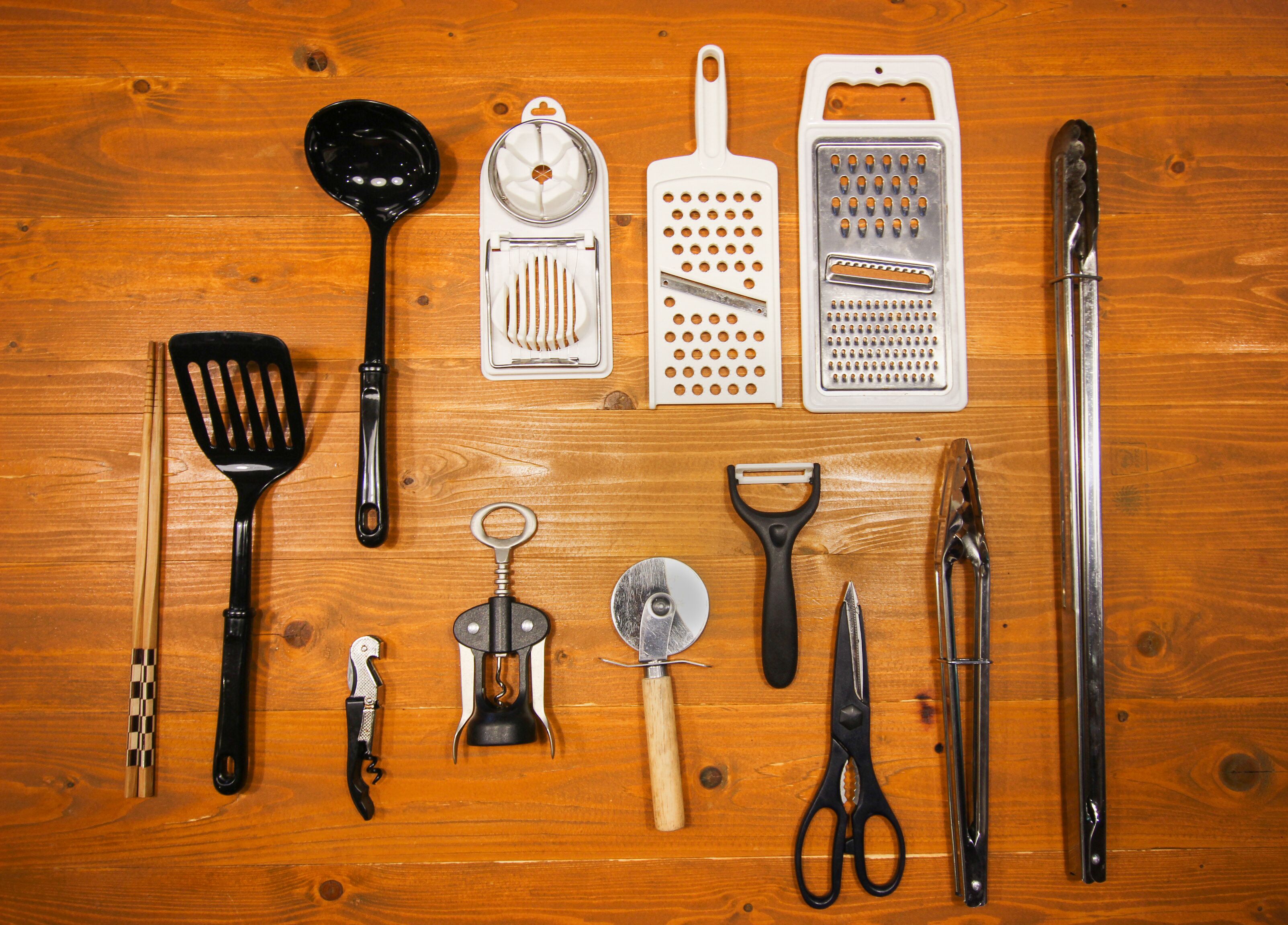Various kitchen utensils and tools arranged on a wooden surface.
