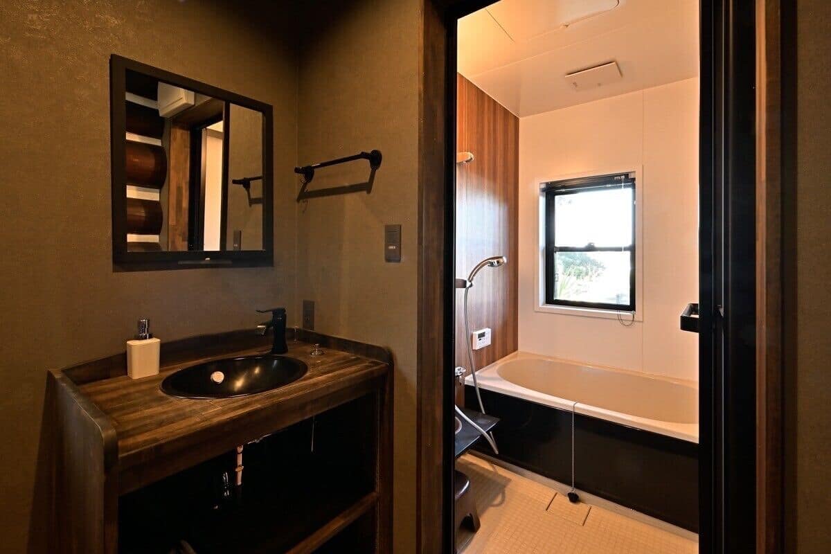 Un baño con tocador de madera, un espejo, una ventana y una bañera.