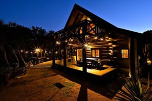 A log cabin with a porch and outdoor seating area, surrounded by trees.