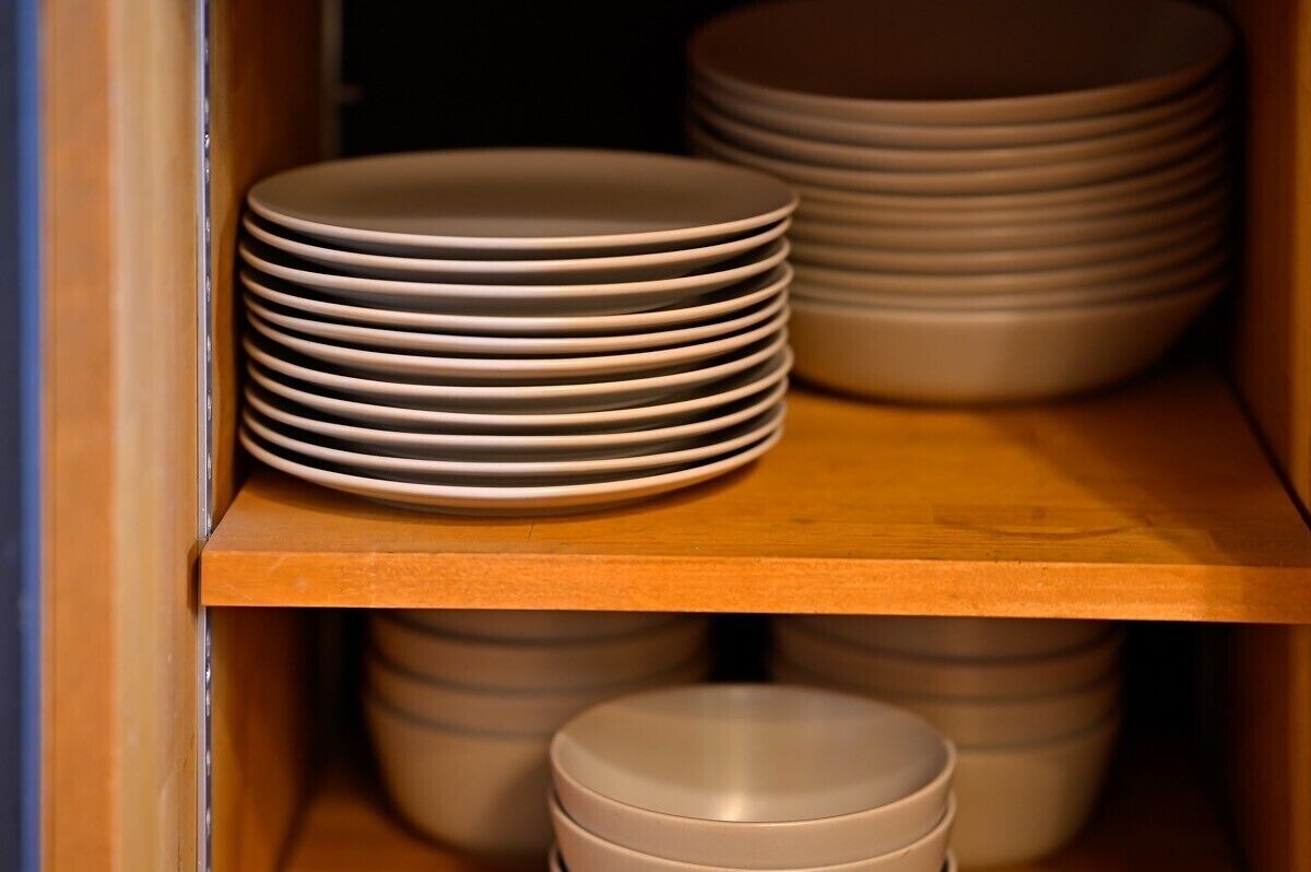 A stack of plates on a wooden shelf.