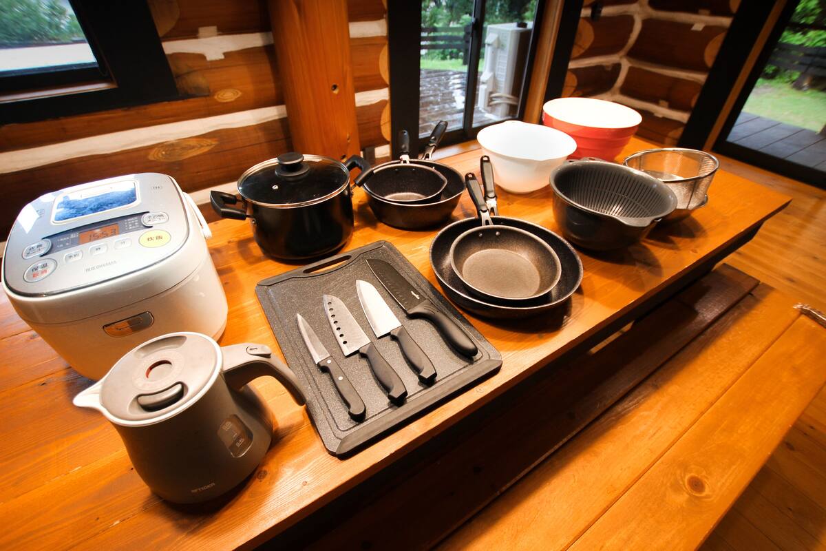 Una encimera de cocina con varios utensilios, una cocedora de arroz y una cafetera.