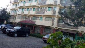 Un immeuble à plusieurs étages doté de balcons, d’une entrée couverte et d’une allée gravillonnée.