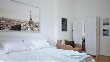 Une chambre à coucher comprenant un lit, un canapé, une armoire et un grand tableau encadré représentant la Tour Eiffel.