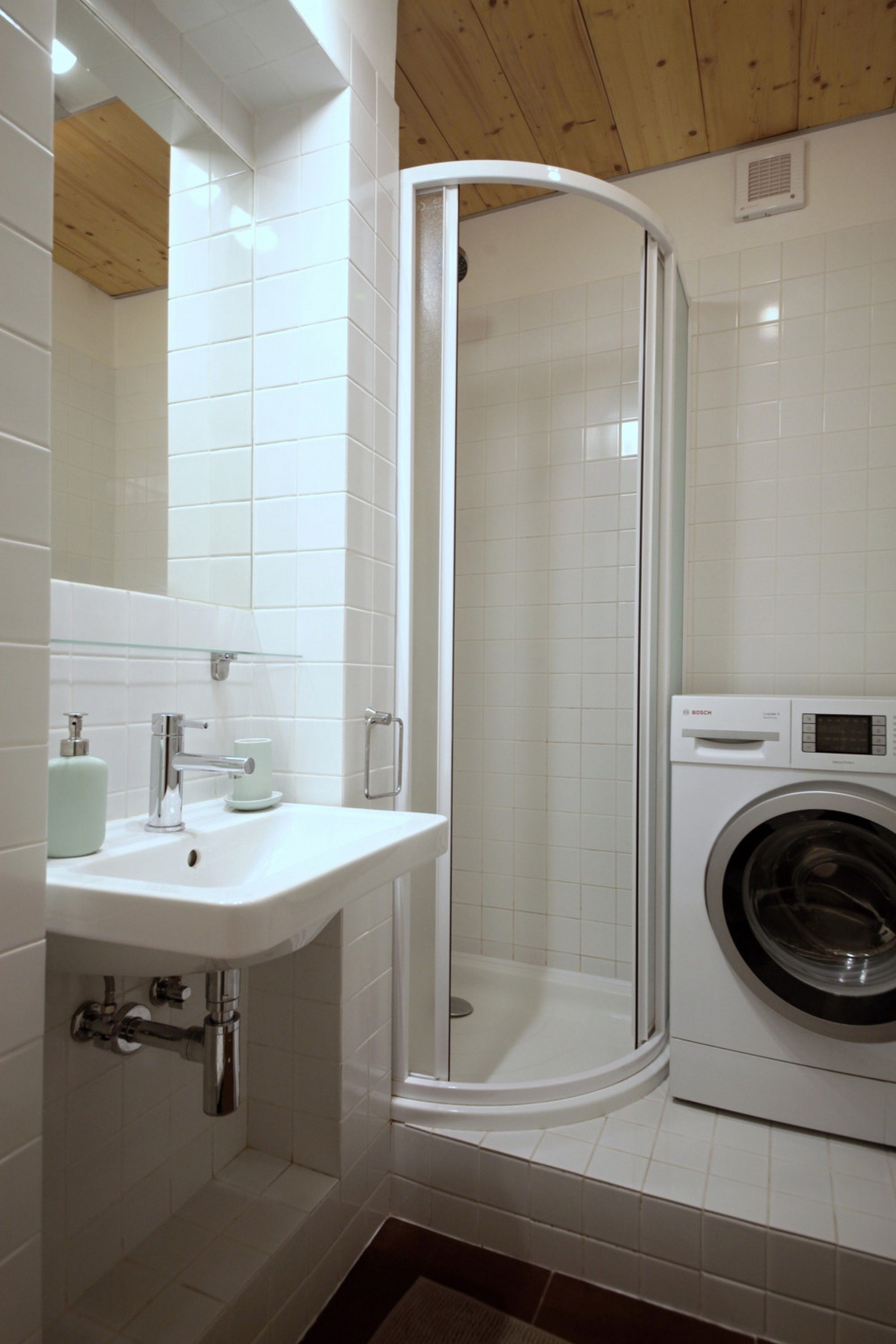 A bathroom with a glass-enclosed shower, a sink, and a washing machine.