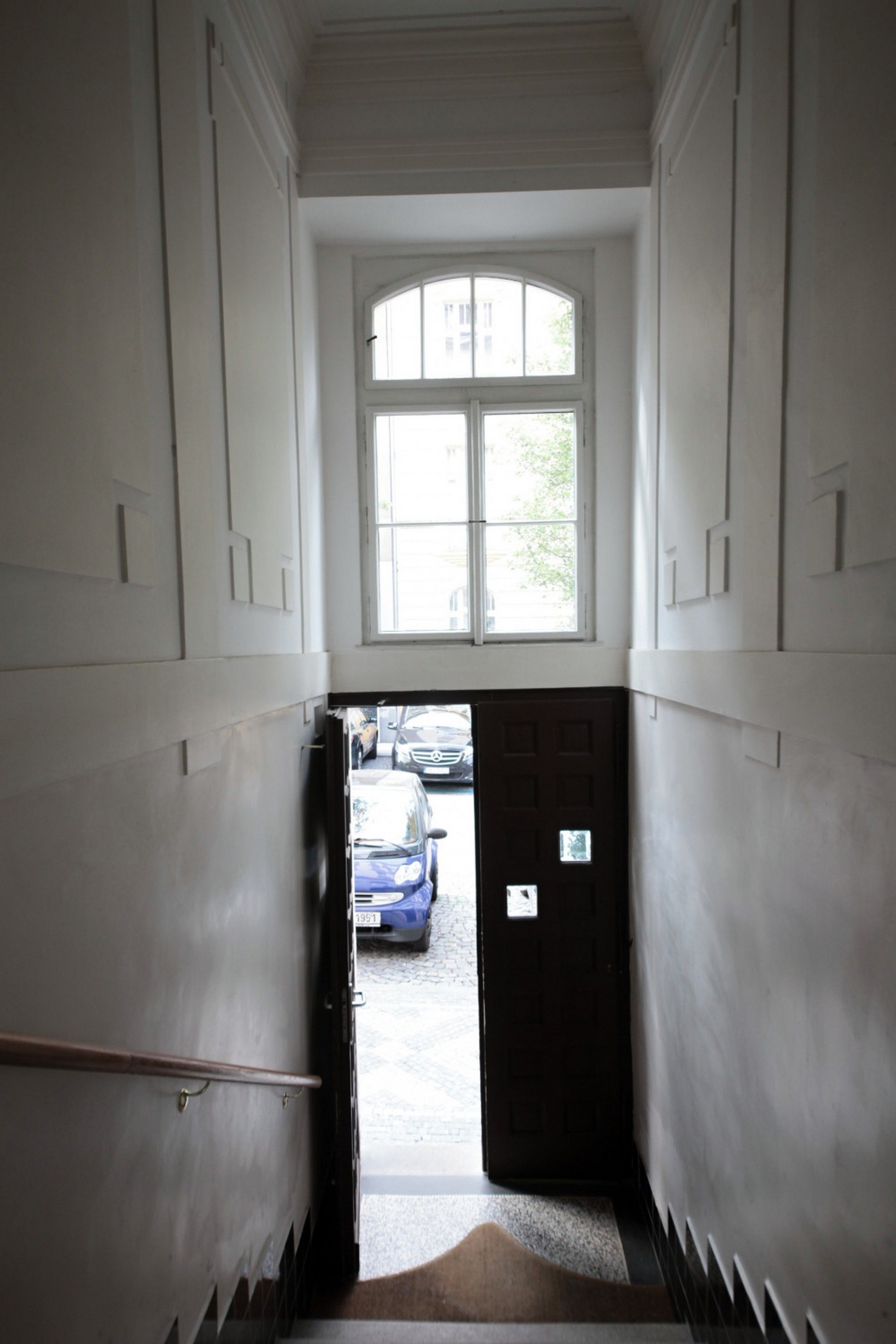 A narrow hallway with a door leading to a parking area.