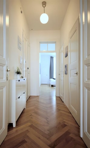 A hallway with wooden flooring, white doors, and a ceiling light fixture. - City Castle Aparthotel (Prague)