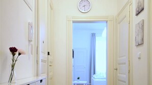 Un pasillo con piso de madera que conduce a un dormitorio con cama y ventana.