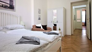 Un dormitorio con una cama, una silla, un armario y un pasillo que lleva a otra habitación.