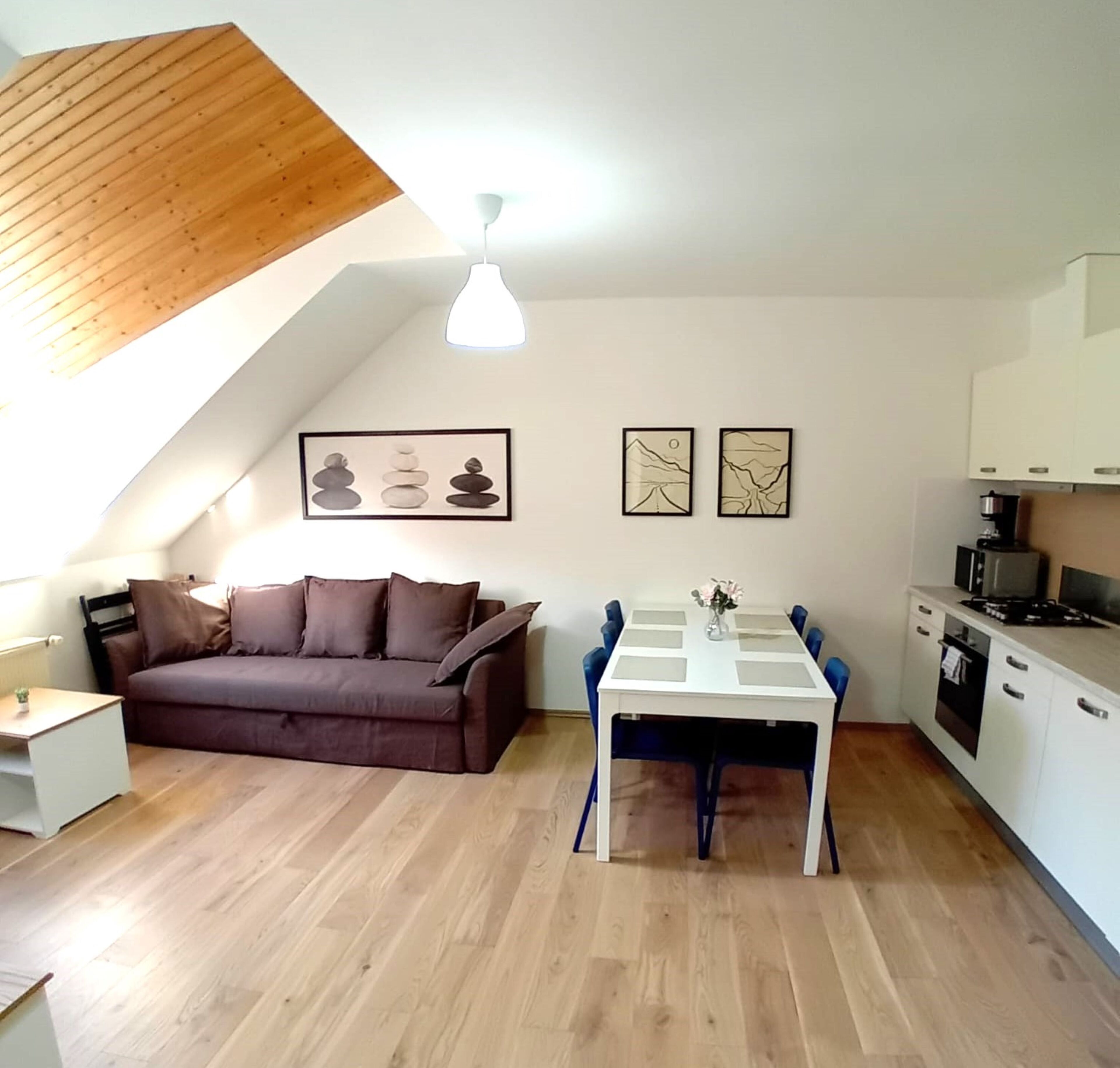 A compact living space with a loft bedroom, a dining area, and a kitchenette.