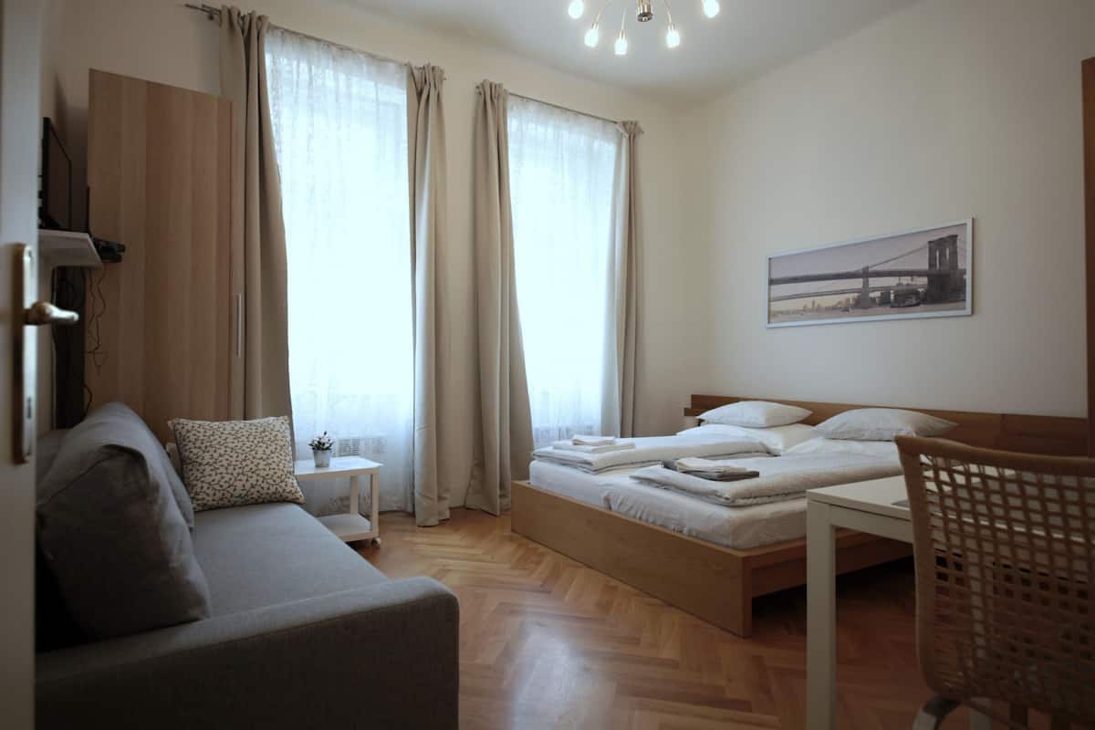 A bedroom with a bed, a sofa, a small table, and a chair.