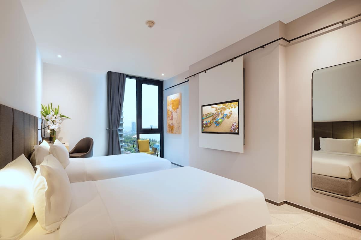 A modern hotel room with two beds, a large mirror, and artwork on the walls.