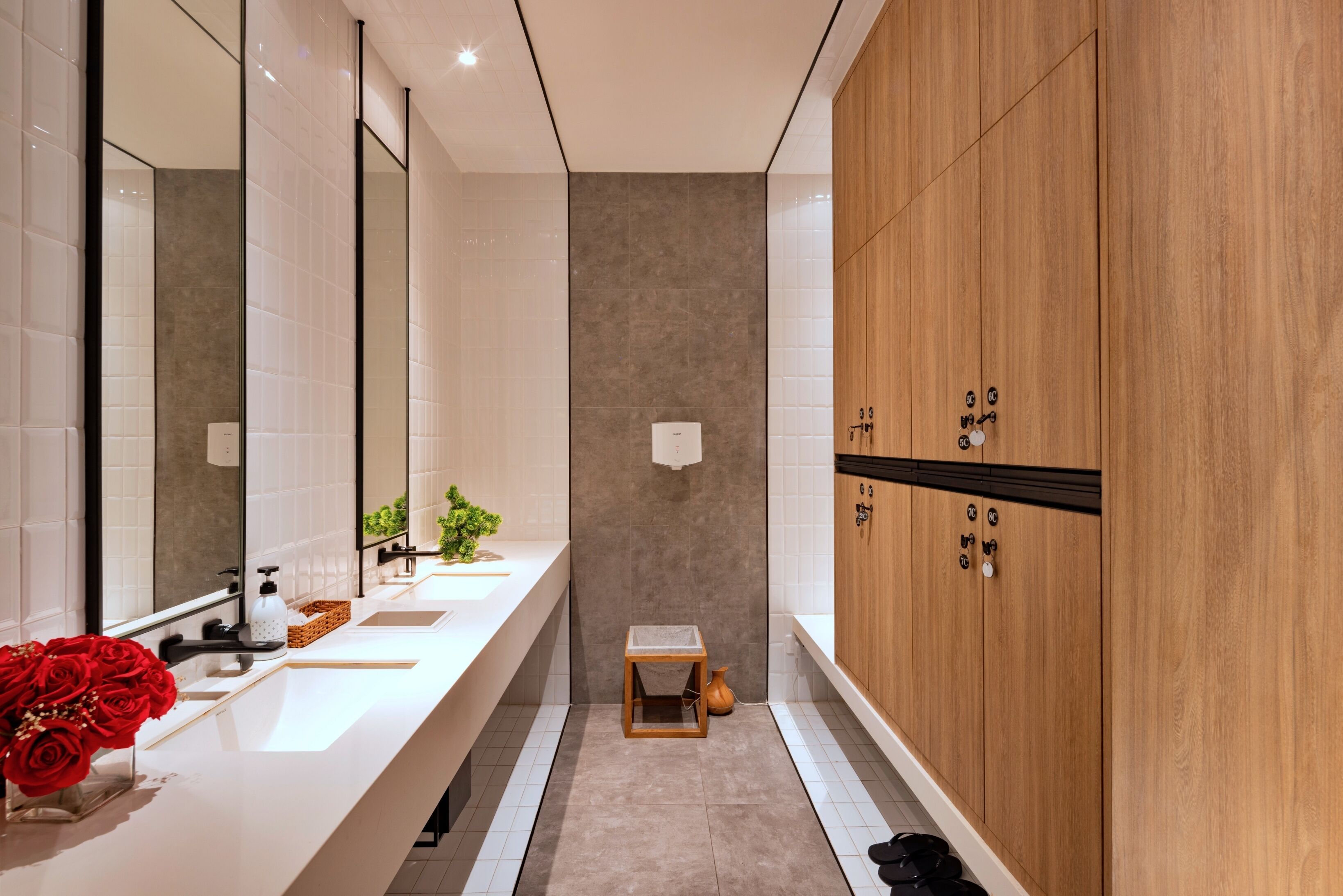 A modern bathroom with a long vanity, a wooden cabinet, and a small stool.