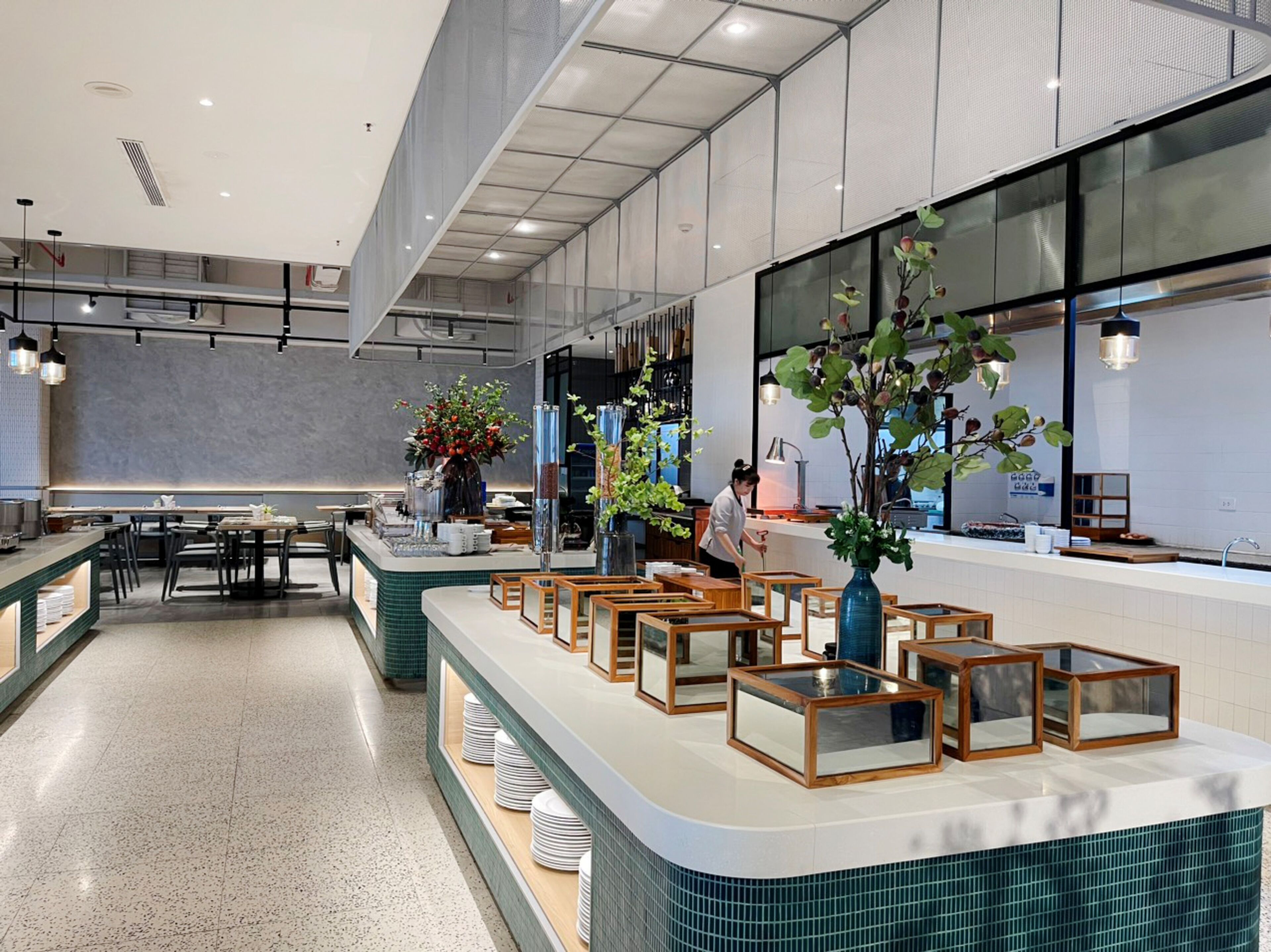 A modern restaurant with a long counter, multiple seating areas, and large windows.