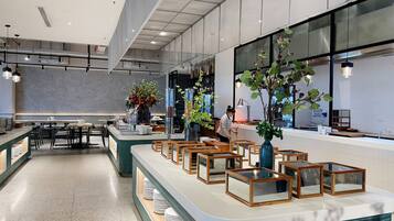 A modern restaurant with a long counter, multiple seating areas, and large windows.