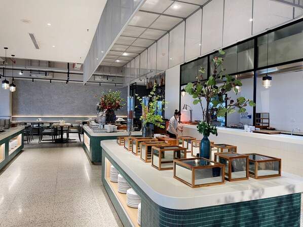 A modern restaurant with a long counter, multiple seating areas, and large windows. - Anya Beach Hotel Quy Nhon (Quy Nhon Nam)