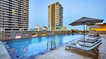 Una piscina al aire libre, sillones reclinables de piscina