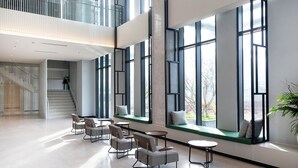 A spacious lobby with high ceilings, large windows, and a mezzanine level. - Anya Beach Hotel Quy Nhon (Quy Nhon Nam)