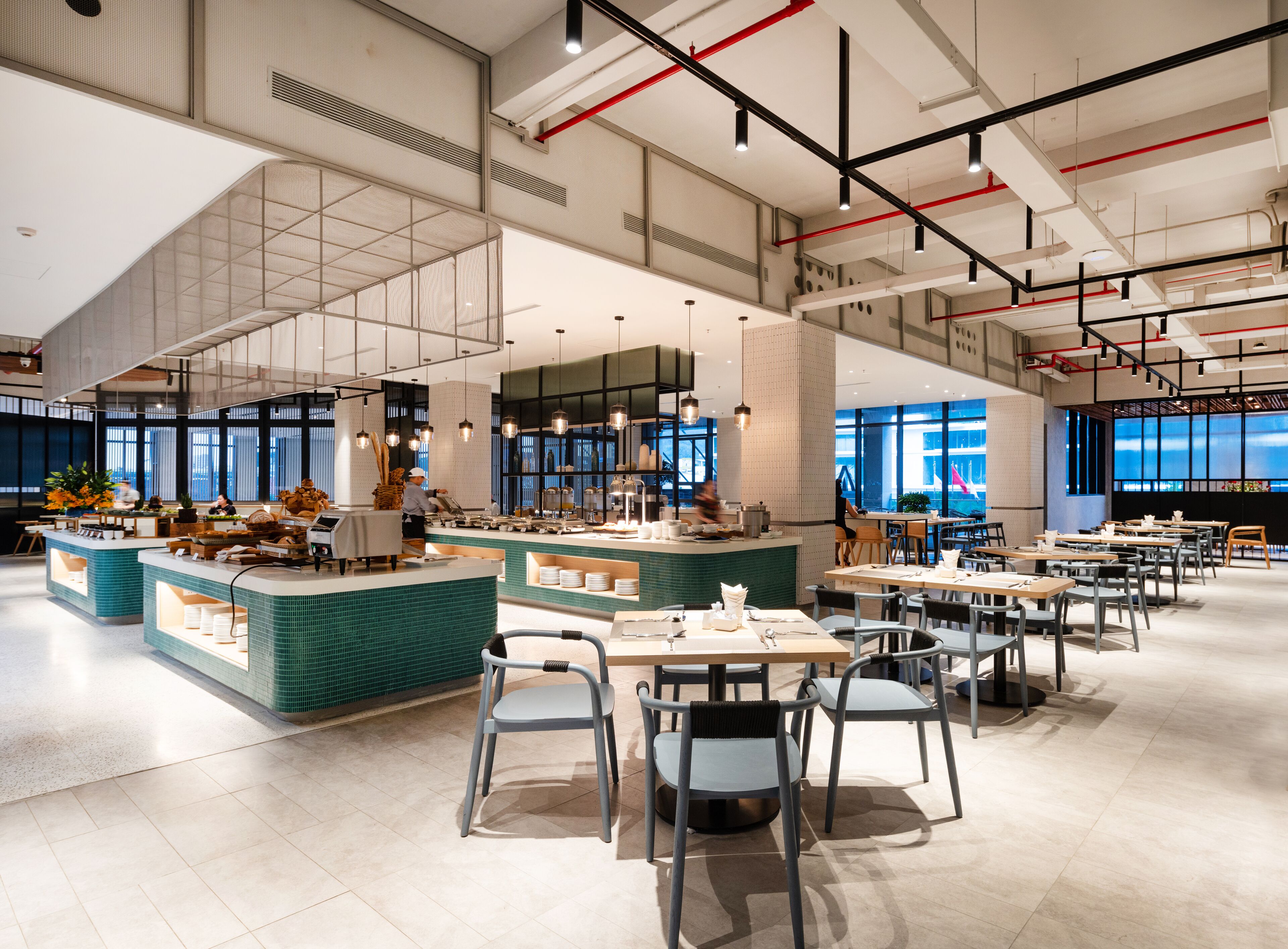 Un restaurante moderno con techos altos, vigas a la vista y amplias ventanas.