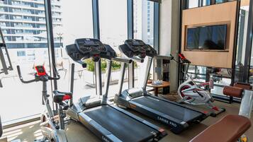 A gym with treadmills, a stationary bike, and a bench.