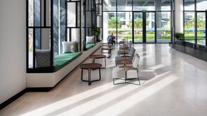 A spacious lobby with a long bench seating area, large windows, and a view of greenery outside. - Anya Beach Hotel Quy Nhon (Quy Nhon Nam)