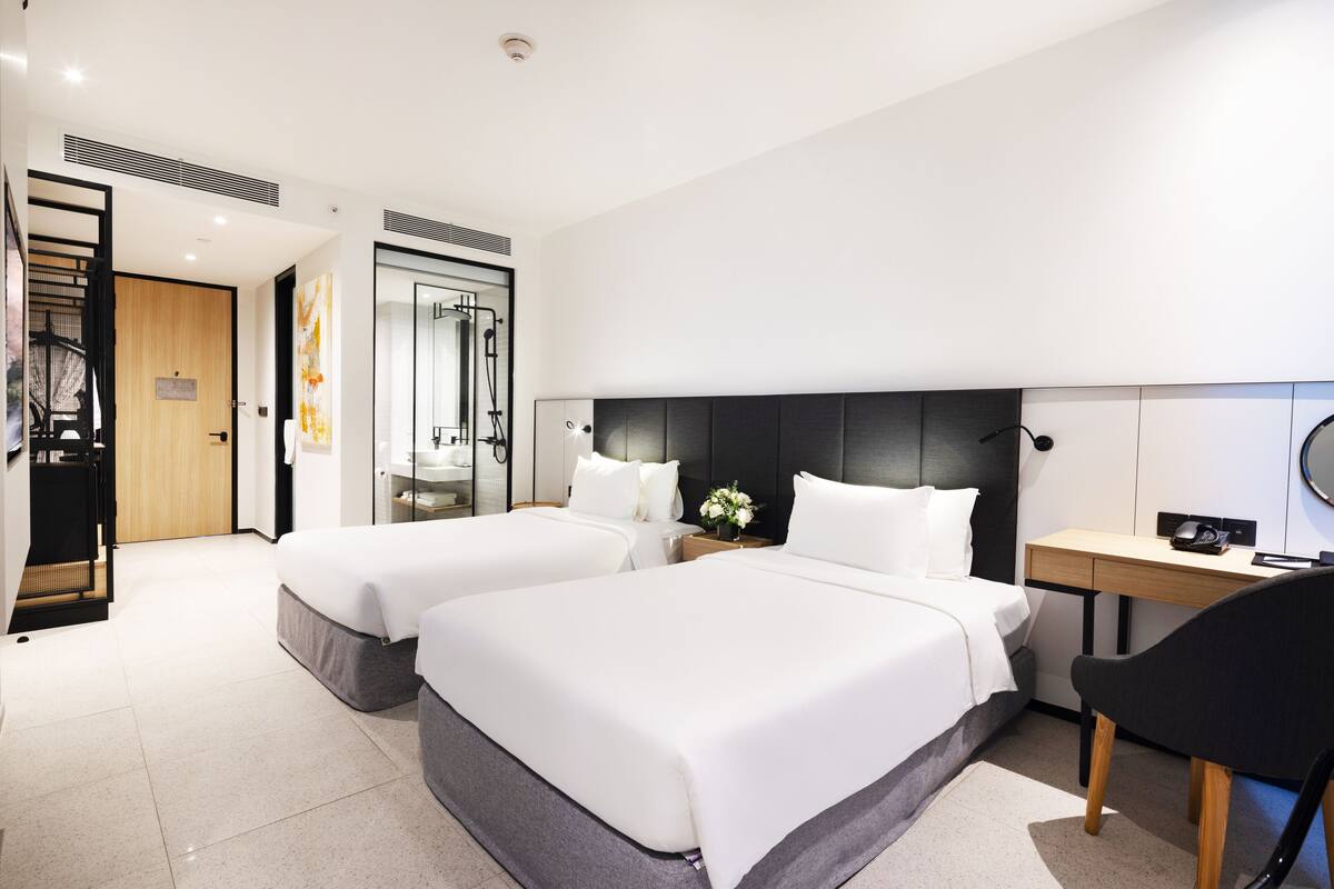 A hotel room with two beds, a desk, and a chair.
